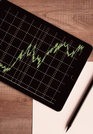 Tablet displaying a financial market chart on a wooden desk